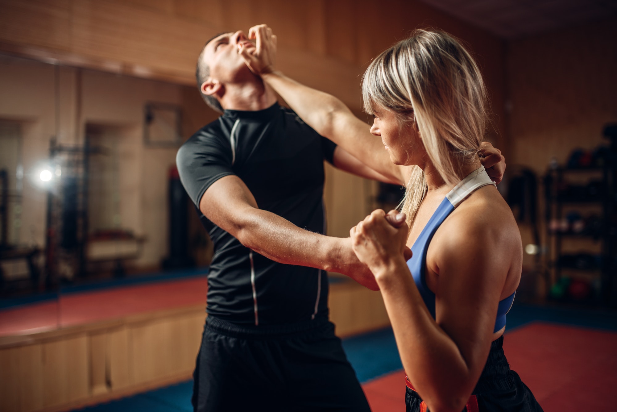 Une femme se défend face à un agresseur dans un scénario d'attaque dans un cours de self-défense avec son entraîneur