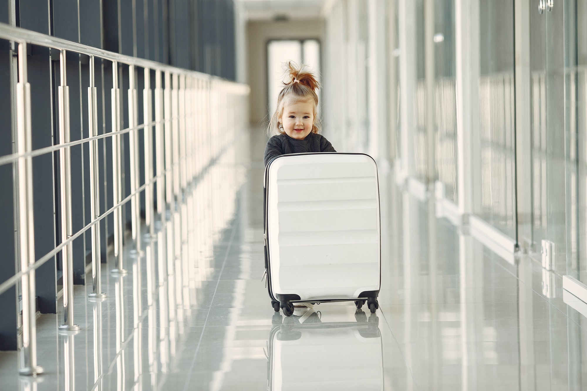 Petite fille avec une valise dans un couloir d'aéroport