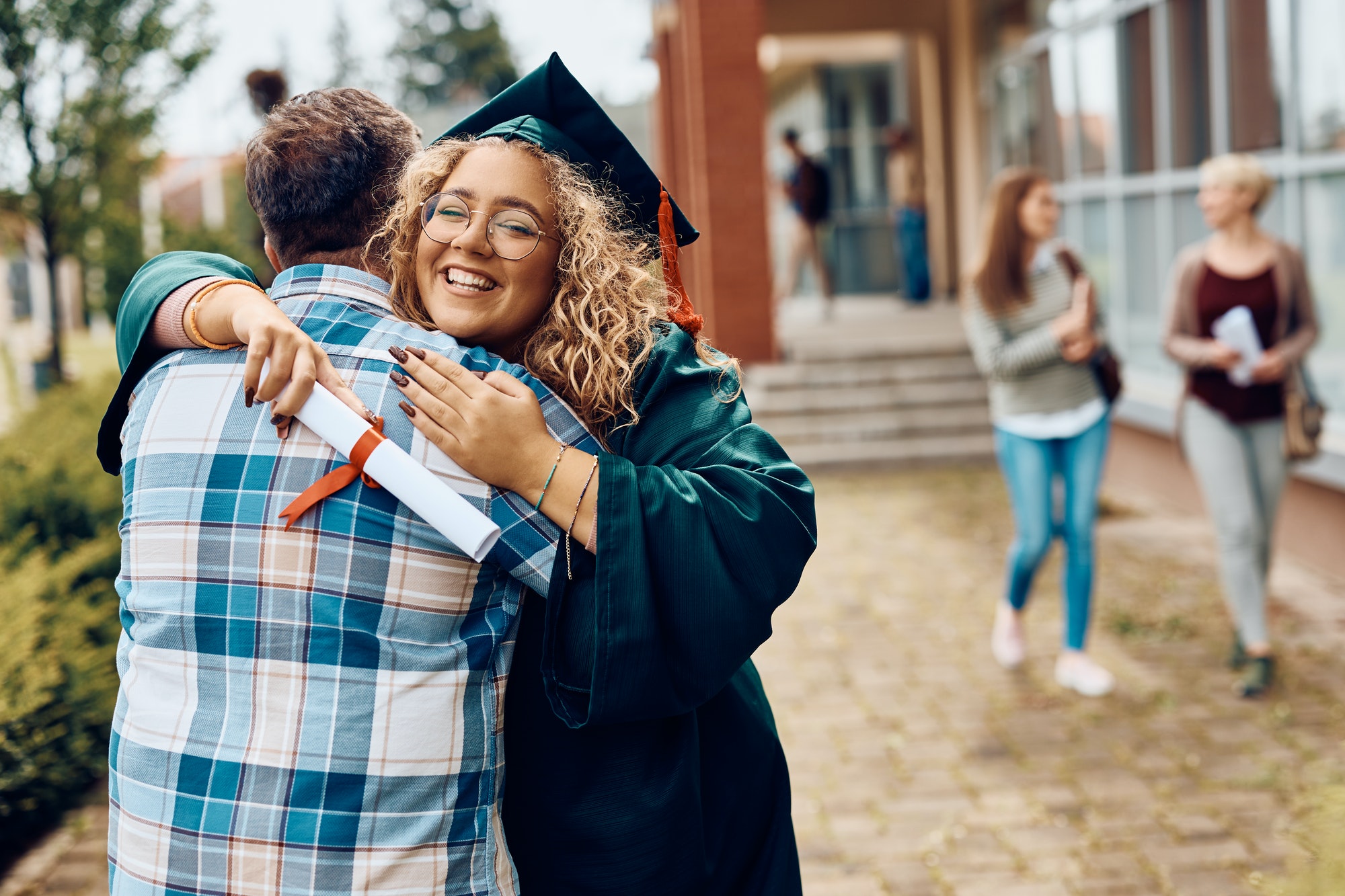 Happy graduate student embracing her father after graduation ceremony.