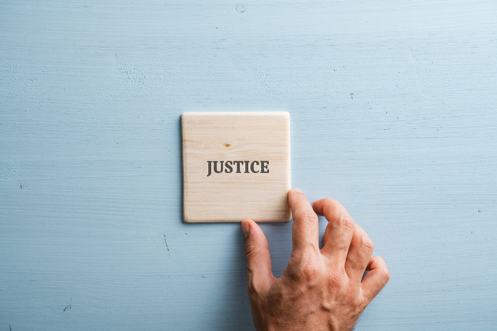 Le mot justice écrit sur du bois avec une main